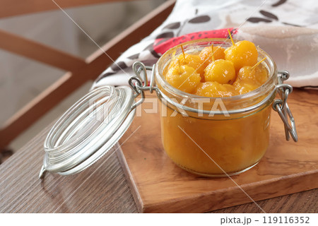 Glass jar of apple jam on wooden olive board. Homemade fruit jams from garden. Kitchen interior and organic food. Glass jar of apple jam on wooden olive board. Homemade fruit jams from garden. Kitchen interior and organic food. 119116352