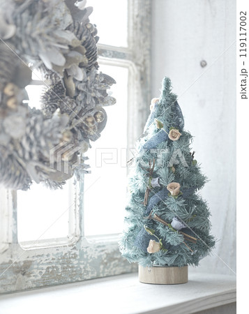 窓辺に飾られたクリスマスリースとクリスマスツリー 119117002