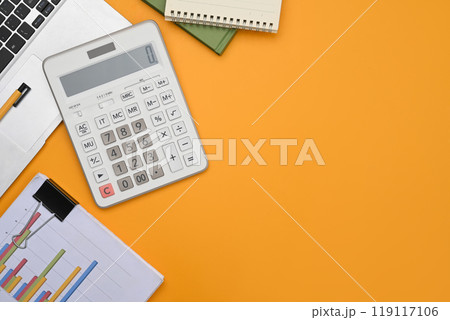 A calculator, laptop, financial reports and notepad on yellow background with space 119117106