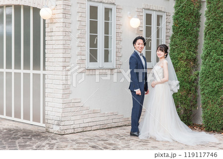 結婚式で結婚式場の庭で腕を組む新郎新婦（ガーデンウェディング） 119117746