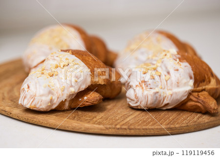 Delicious fresh croissants on wooden tray on white table, closeup Delicious fresh croissants on wooden tray on white table, closeup 119119456