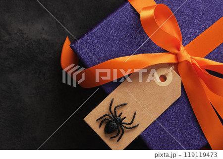Halloween gift wrapped in purple paper with orange ribbon and empty label with spider on it Halloween gift wrapped in purple paper with orange ribbon and empty label with spider on it 119119473