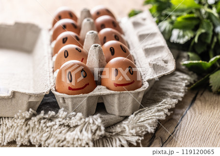Cute smiling fresh eggs in a paper carton on the kitchen table Cute smiling fresh eggs in a paper carton on the kitchen table 119120065