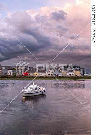 Sunset in Galway City with small boat in the foreground and storm clouds glowing pink and grey hues 119120508