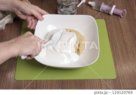 Dough preparation process. Woman mix in bowl powdered sugar, almond flour and beaten egg white using silicone spatula. Baking macarons at home. Close-up of hands. Dough preparation process. Woman mix in bowl powdered sugar, almond flour and beaten egg white using silicone spatula. Baking macarons at home. Close-up of hands. 119120769