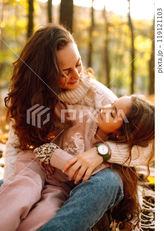Stylish young Mother and daughter walking in the autumn forest at sunset. Family on a walk. Stylish young Mother and daughter walking in the autumn forest at sunset. Family on a walk. 119121103