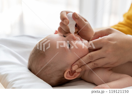 Woman using nasal spray for infant baby loving mother taking care of her newborn child 119121150