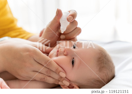 Mother dripping nasal drops for her infant at home Mother dripping nasal drops for her infant at home 119121151