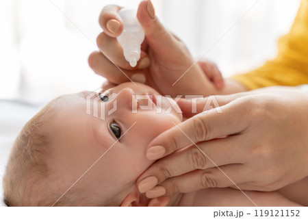 Woman using nasal spray for infant baby loving mother taking care of her newborn child Woman using nasal spray for infant baby loving mother taking care of her newborn child 119121152