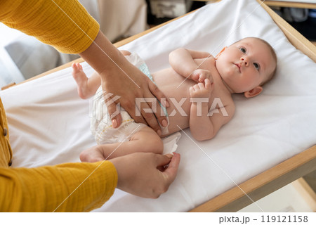 Mother changing her newborn's diaper in the nursery ensuring the baby's hygiene Mother changing her newborn's diaper in the nursery ensuring the baby's hygiene 119121158
