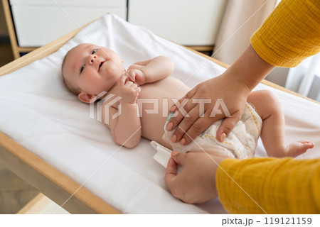 Mother changing her baby's diaper taking care of her newborn child 119121159