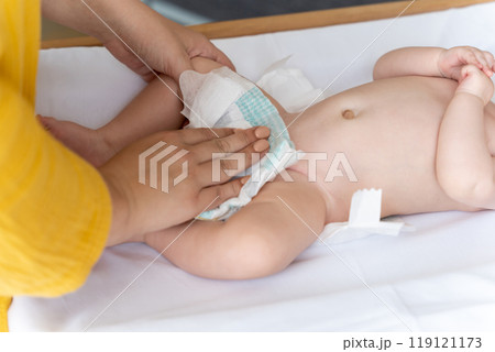 Mother changing her baby's diaper taking care of her newborn child Mother changing her baby's diaper taking care of her newborn child 119121173