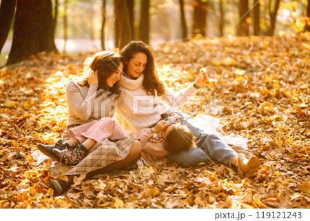 The homosexual family playing with her daughter in the autumn forest. The adventure is more fun. 119121243