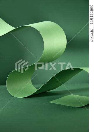A delicate green ribbon curves and swirls gracefully against a deep emerald background, creating a captivating composition space for displaying text or products. A delicate green ribbon curves and swirls gracefully against a deep emerald background, creating a captivating composition space for displaying text or products. 119121660