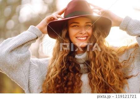 Stylish woman in sweater and hat enjoys autumn nature. People, freedom, lifestyle, travel concept. 119121721