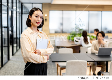 ノートパソコンを抱えてコチラを見つめる女性 119123356