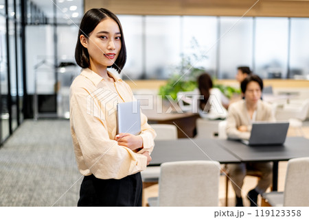 ノートパソコンを抱えてコチラを見つめる女性 119123358