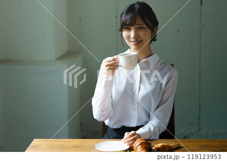 朝の落ち着いた雰囲気の中で一杯のコーヒーを飲む若い女性 119123953