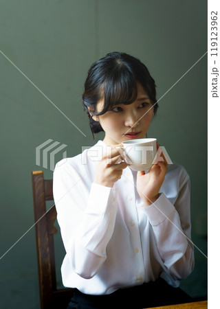 朝の落ち着いた雰囲気の中で一杯のコーヒーを飲む若い女性 朝の落ち着いた雰囲気の中で一杯のコーヒーを飲む若い女性 119123962