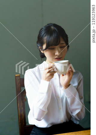 朝の落ち着いた雰囲気の中で一杯のコーヒーを飲む若い女性 119123963