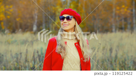 Autumn portrait of beautiful happy mature woman in red french beret hat, jacket, glasses outdoors 119125422