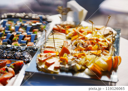 banquet table with appetizers. In the foreground is a plate of sliced cheese 119126065
