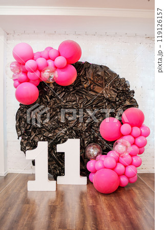 A decor of pink balloons and the number eleven for a birthday. A decor of pink balloons and the number eleven for a birthday. 119126157