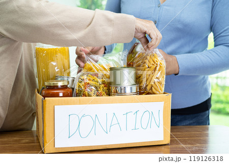 Volunteers putting various dry food in donation box for help people. 119126318