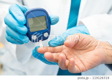 Doctor check diabetes from finger blood sugar level with finger lancet. Doctor check diabetes from finger blood sugar level with finger lancet. 119126319