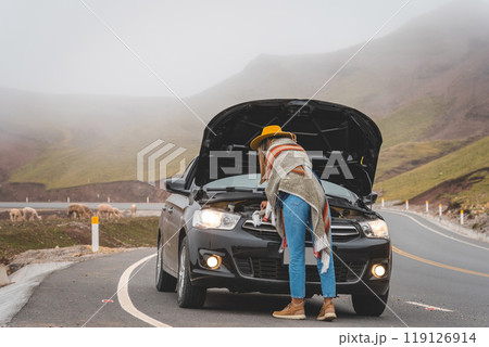 A woman is standing next to a black car with the hood up, tourist in the peruvian andes 119126914
