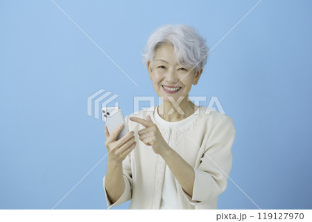 ブルーバックのスマホを操作する白髪のシニア女性 119127970