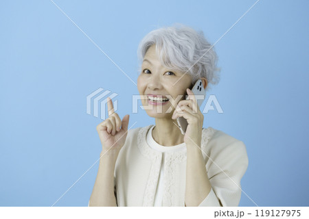 ブルーバックのスマホを手に1番のポーズをする白髪のシニア女性 119127975