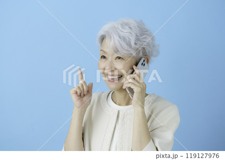 ブルーバックのスマホを手に1番のポーズをする白髪のシニア女性 119127976