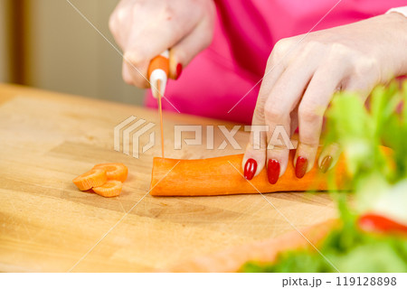 Woman cutting carrot on kitchen board 119128898