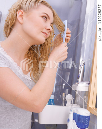 Woman combing her long hair in bathroom Woman combing her long hair in bathroom 119129277