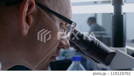 In bright medical laboratory: Professional microbiologist looking under microscope In bright medical laboratory: Professional microbiologist looking under microscope 119129702