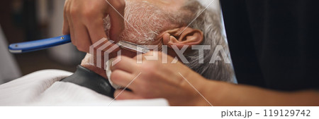 Close-up of barber using straight razor on male neck, carefully shaving around edges. Precision and attention to detail 119129742