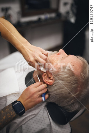 Barber gently using scissors, carefully attending to edges of the beard. Grooming session. Senior man visiting barber shop Barber gently using scissors, carefully attending to edges of the beard. Grooming session. Senior man visiting barber shop 119129747