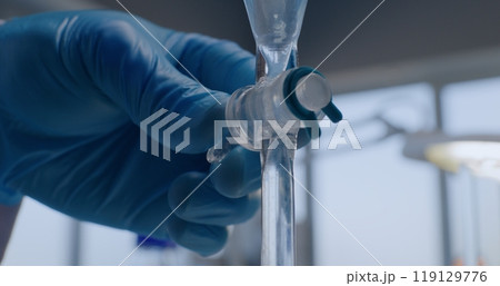 Close up of chemist pouring liquid from pipette into glass bottle 119129776