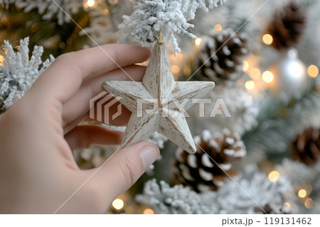 Decorating a festive tree with a handmade star ornament during the holiday season 119131462