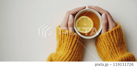 Cozy hands holding a warm cup of tea with a slice of lemon in a knitted sweater Cozy hands holding a warm cup of tea with a slice of lemon in a knitted sweater 119131726
