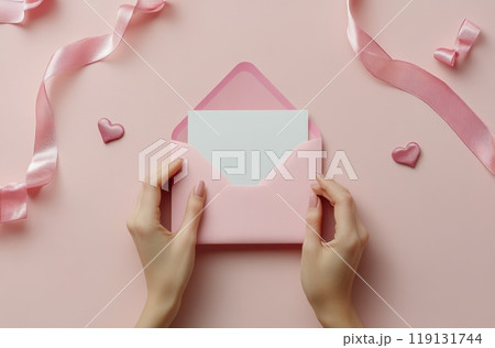 Delicate hands sealing a pink envelope with a letter on a pastel pink background 119131744