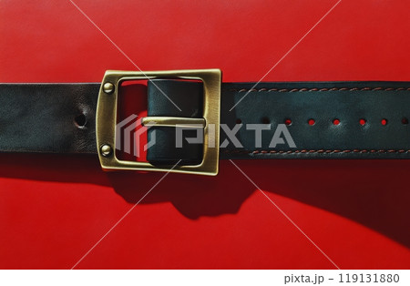 A close-up of a black leather belt with a brass buckle against a smooth red background A close-up of a black leather belt with a brass buckle against a smooth red background 119131880