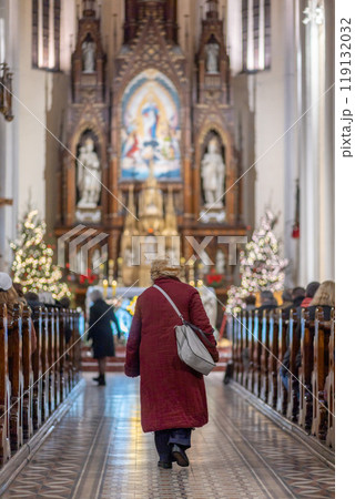 Back view of elderly woman walks down the aisle during Christmas Mass. The Catholic Orthodox Christmas holiday in Europe. Vertical oriental Back view of elderly woman walks down the aisle during Christmas Mass. The Catholic Orthodox Christmas holiday in Europe. Vertical oriental 119132032