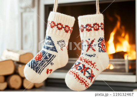Pair of knitted socks with colorful pattern hang by a fireplace 119132467