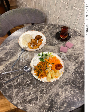 Two plates of diverse cuisine on a marble table, showcasing a combination of colorful vegetables, grains, and meats. an inviting meal setting for a casual dining experience Two plates of diverse cuisine on a marble table, showcasing a combination of colorful vegetables, grains, and meats. an inviting meal setting for a casual dining experience 119132617