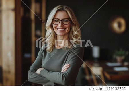 Confident businesswoman with blonde hair and glasses in modern office setting 119132765