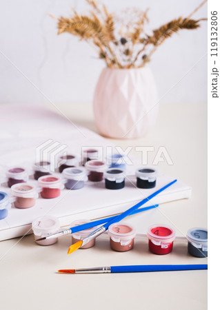 Brushes, multi-colored acrylic paints and canvas for painting by numbers vertical view 119132806