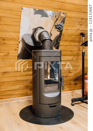 Modern wood-burning stove in cozy wooden cabin interior, showcasing warmth and rustic atmosphere Modern wood-burning stove in cozy wooden cabin interior, showcasing warmth and rustic atmosphere 119133667