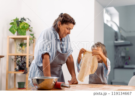 Girl holding flattened dough at table while baking Girl holding flattened dough at table while baking 119134667